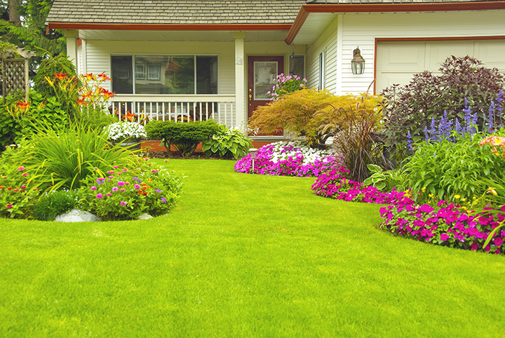 Cream house with colorful flower beds and a nice green lawn