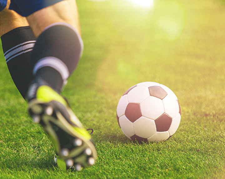 Close up of soccer players feet going to kick the ball on soccer turf