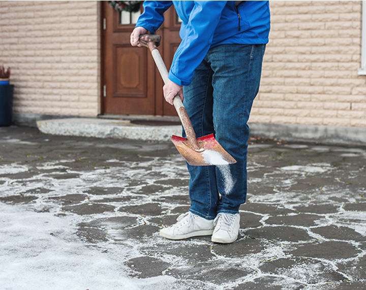 Man spreading salt with a shovel in driveway
